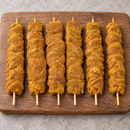 Six raw Large Satay Chicken Kebabs, 125g each, arranged on a wooden board
