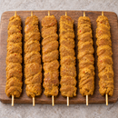 Six raw 130g XL satay chicken kebabs on bamboo skewers, arranged vertically on a wooden board.