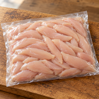 Fresh chicken tenderloins in a clear vacuum-sealed bulk pack on a rustic oak board.