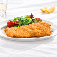 Universal 220g crumbed chicken thigh schnitzel on a white plate with mixed salad leaves and cherry tomatoes; serving suggestion.